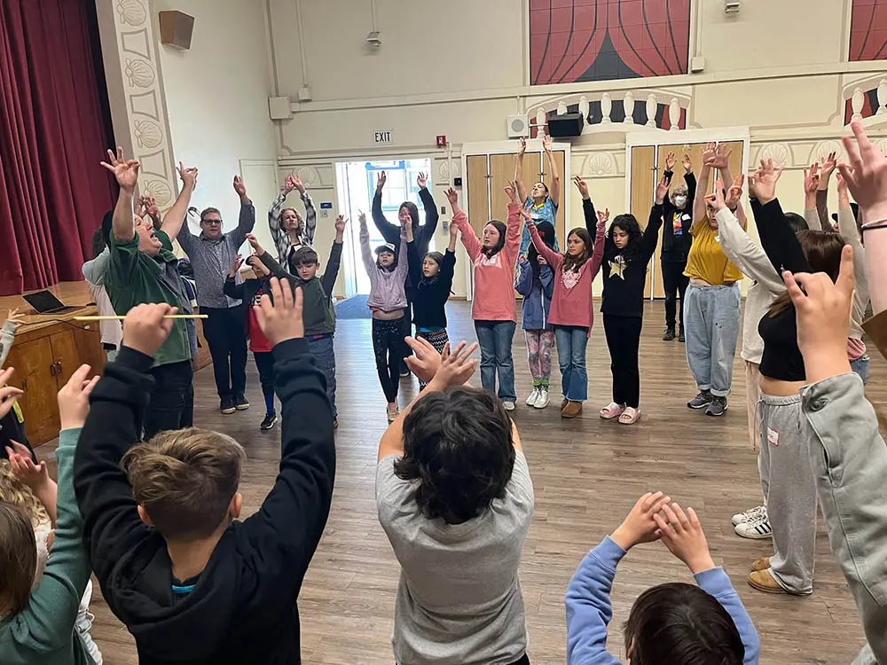 Group of different ages dancing with arms raised.